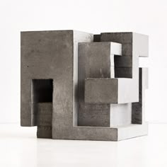 a sculpture made out of concrete blocks sitting on top of a white floor next to a wall