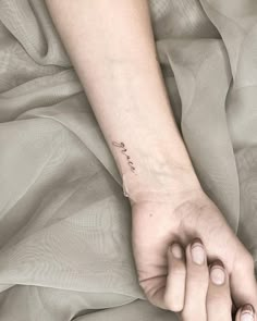 a woman's hand with a small tattoo on her left wrist and the word love written in cursive writing