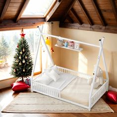 a white crib next to a christmas tree in a room with wooden floors and beams