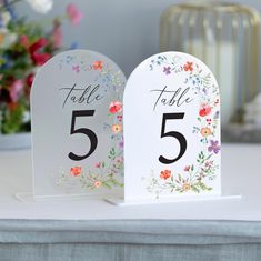 two white table numbers with flowers on them