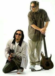 two men standing next to each other with guitars