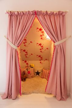 a pink and white room with stars on the wall, curtains open to let light in