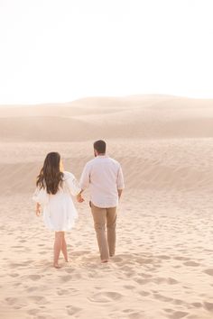 a man and woman walking in the desert holding hands