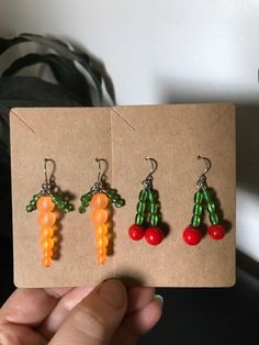 three pairs of fruit shaped earrings are shown in front of a brown piece of paper