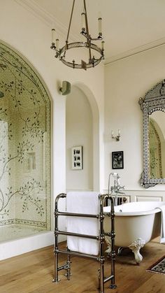 a bathroom with a claw foot bathtub, mirror and chandelier