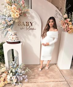 a pregnant woman standing in front of a floral display