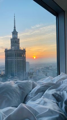 the sun is setting in front of a window with a view of a large building