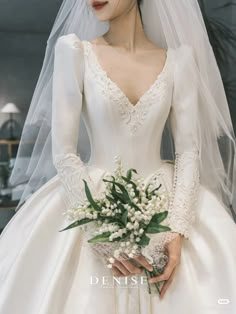 a woman wearing a wedding dress and veil holding a bouquet of flowers in her hand