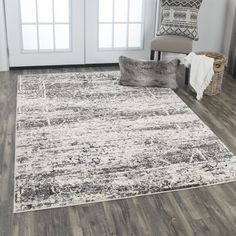 a large area rug in a living room with wooden floors and white walls, along with a gray chair