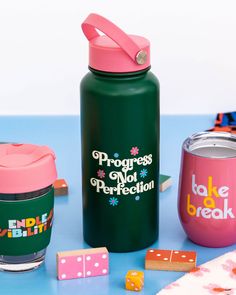 a green water bottle with pink lid next to other items on a blue table top