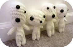 three crocheted white stuffed animals sitting next to each other on the floor in front of a wall