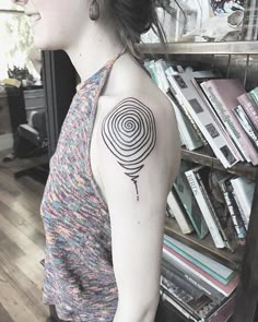 a woman with a black and white tattoo on her arm, holding a bookcase