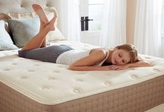 a woman laying on top of a mattress in a bedroom