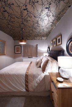 a bedroom with a bed, nightstands and pictures on the wall above it that has branches painted on the ceiling