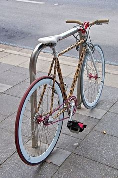 a bicycle chained to a pole on the sidewalk