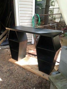 a black desk sitting on top of a wooden pallet