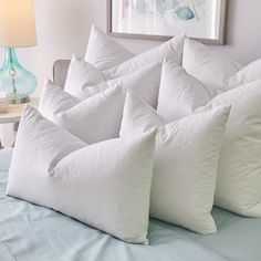 a bunch of pillows sitting on top of a bed