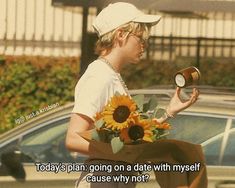 a young man holding a sunflower and a coffee cup