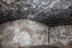 an old stone room with a light on the wall and brick flooring in it