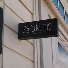 a black sign hanging from the side of a building that says form fit on it