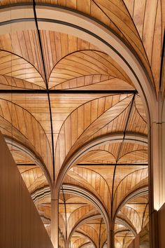 the inside of a building with wooden ceilinging and arched arches on both sides is lit by lamps