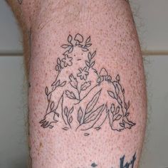 a close up of a person's leg with tattoos on it and flowers in the middle