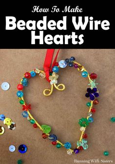 a heart shaped beaded necklace with red ribbon and buttons on the ground next to it