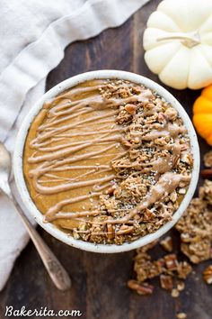 a white bowl filled with granola and topped with chocolate frosting next to mini pumpkins