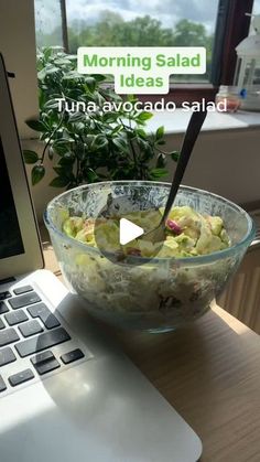 a bowl of food sitting on top of a wooden table next to a laptop computer