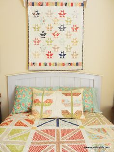 a quilt hanging on the wall above a bed