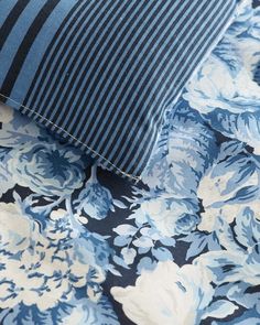 a blue and white flowered fabric with black stripes on it's side, next to a striped pillow