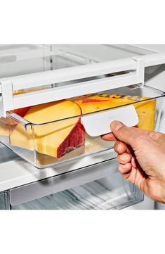 a person is taking food out of an open refrigerator door with their left hand on the tray