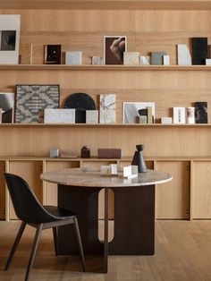 a table with two chairs in front of shelves filled with books and other items on it