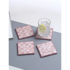 four square pink and white coasters on a table with a drink in the middle