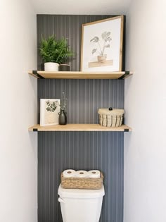 a toilet sitting in a bathroom next to two shelves with plants on top of it