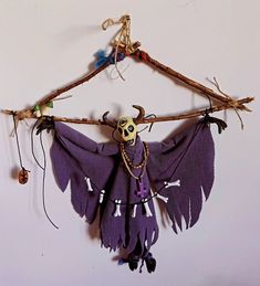 a purple bat hanging on a wall with beads and chains attached to it's wings