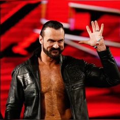 a man with his hand up in the air while wearing a leather jacket and no shirt