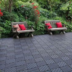 two wooden benches sitting next to each other on a brick walkway surrounded by greenery