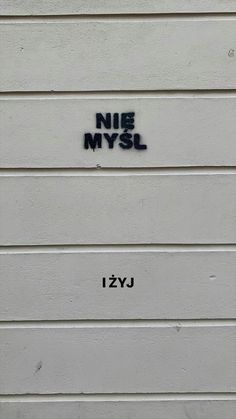 graffiti written on the side of a white building that says nie nys lyj