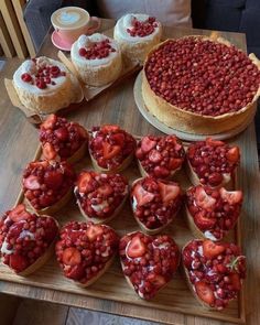 there are many desserts on the table with strawberries in cups next to them