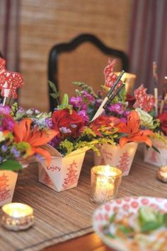 there are many small cups with flowers in them on the table next to some candles