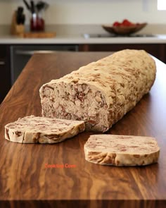 a loaf of bread sitting on top of a wooden counter next to two slices of bread