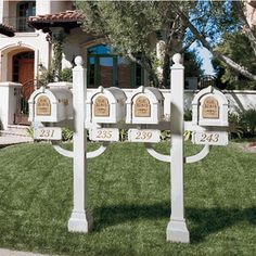 a white mailbox in front of a house with trees and grass on the lawn