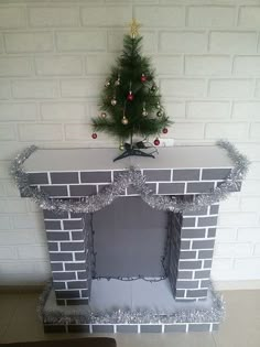 a christmas tree is placed on top of a brick fireplace with tinsel around it