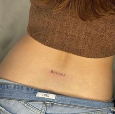 a woman's stomach with the word divine tattooed on it