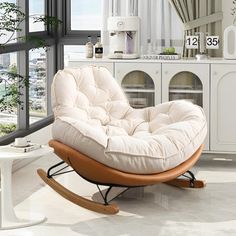 a white living room with a rocking chair and large window overlooking the cityscape