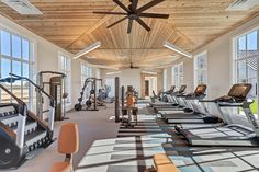 a gym with rows of treadmills, exercise machines and windows overlooking the ocean