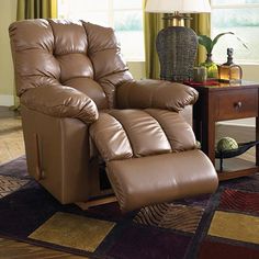 a brown recliner chair sitting on top of a rug in front of a window