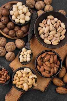 nuts in bowls and spoons on a wooden cutting board next to some walnuts