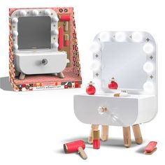 a white vanity with lights and mirror in front of it, next to a red brush